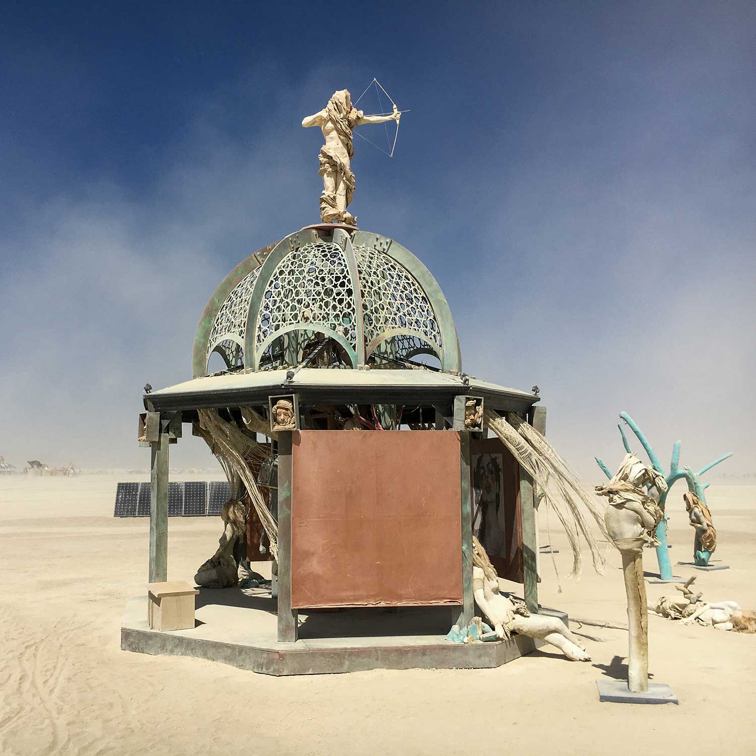 Secretly Abandoned Spaces by day: the weathered green lattice dome topped by an archer figure, with turquoise trees nearby