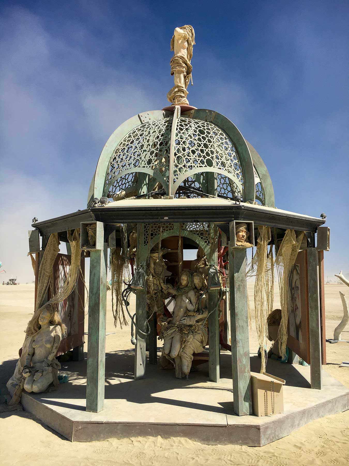 Front view of the structure by day, the embracing pair seated beneath the dome and a figure on the front step
