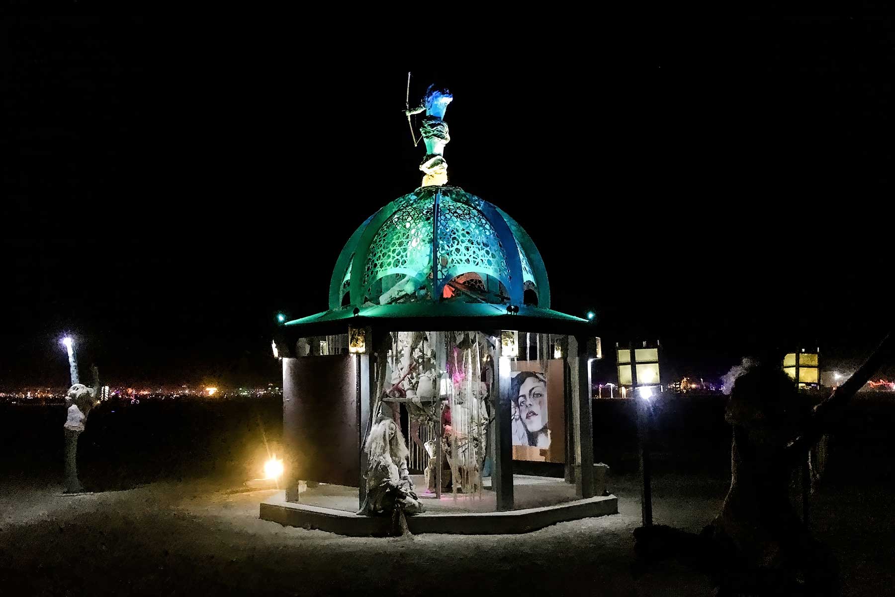 Secretly Abandoned Spaces at night, its dome lit in teal beneath the archer figure