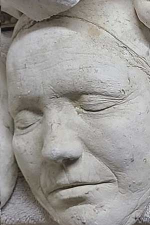 Close-up of a cast face with closed eyes and a deeply lined brow